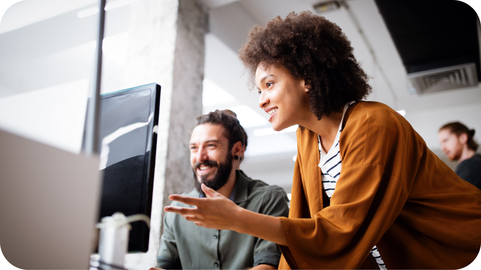 Lady explaining to man in front of a desktop computer