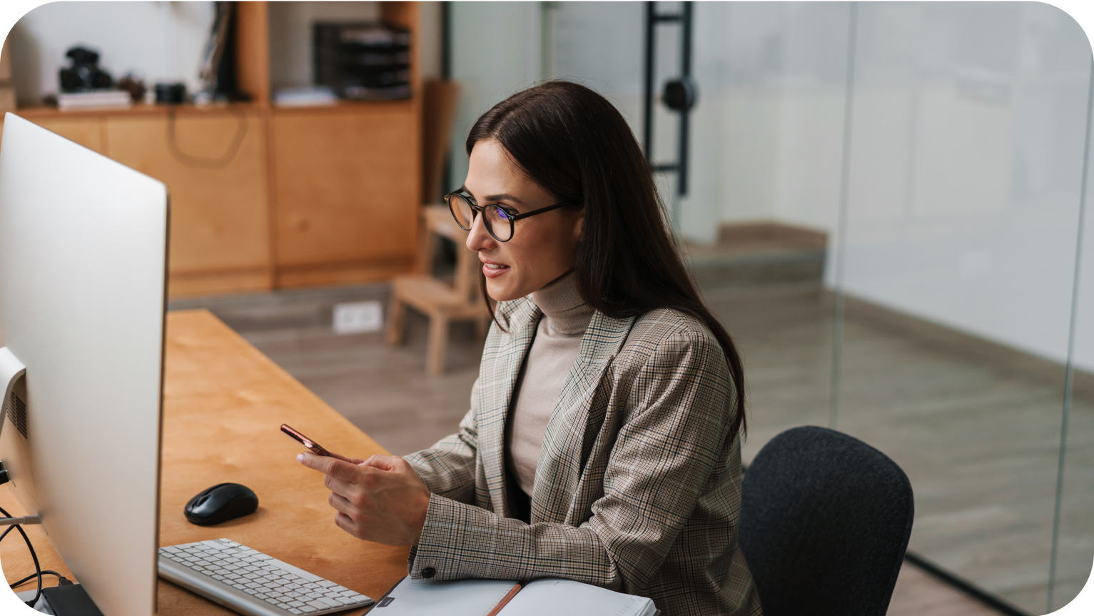 Lady with long hair and glasses doing work at work station